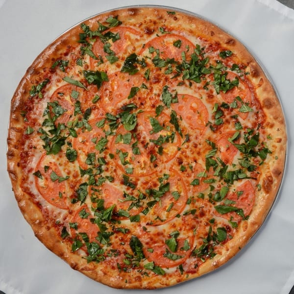 A Beach Pizza Margherita pizza, topped with sliced tomatoes, melted cheese, and fresh basil.